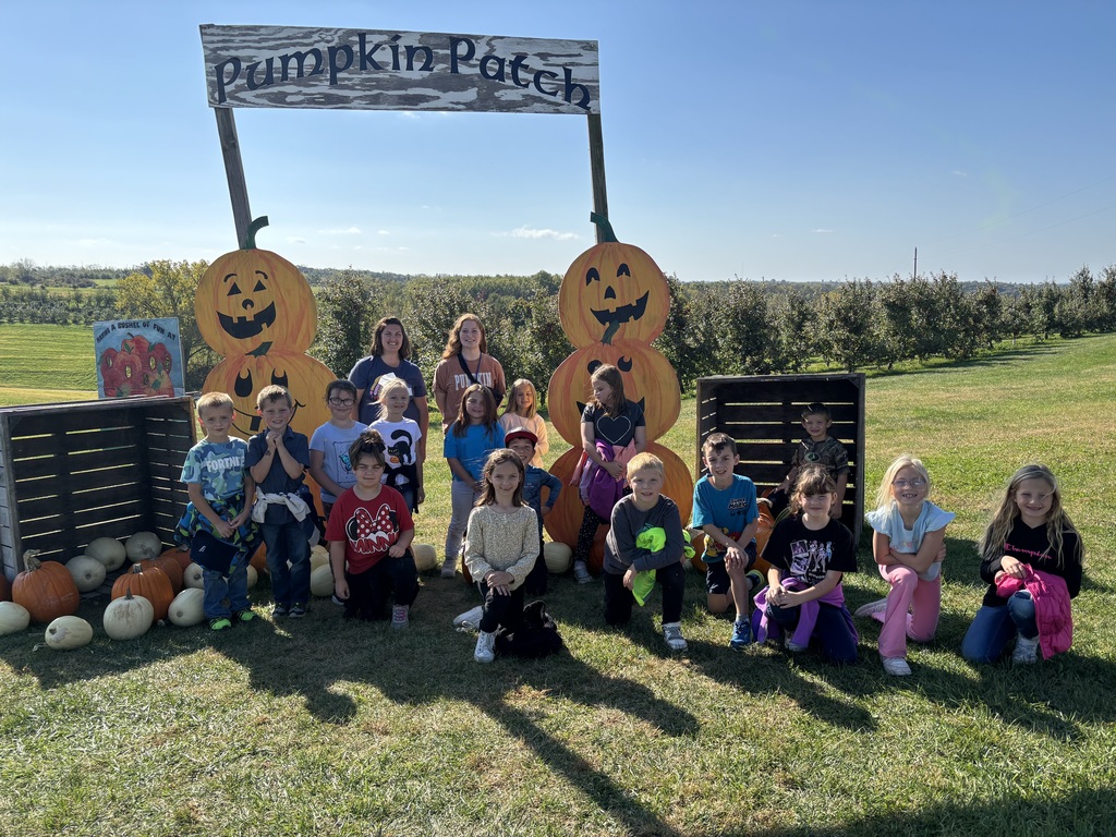 2nd grade students pose for a picture at the pumpkin patch entrance at the orchard