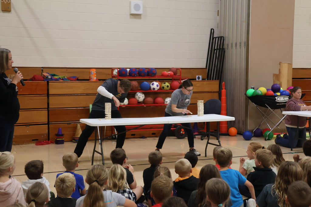 2 teachers compete in a jenga style challenge in the gym