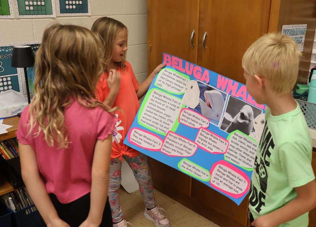 students show off their animal posters to classmates
