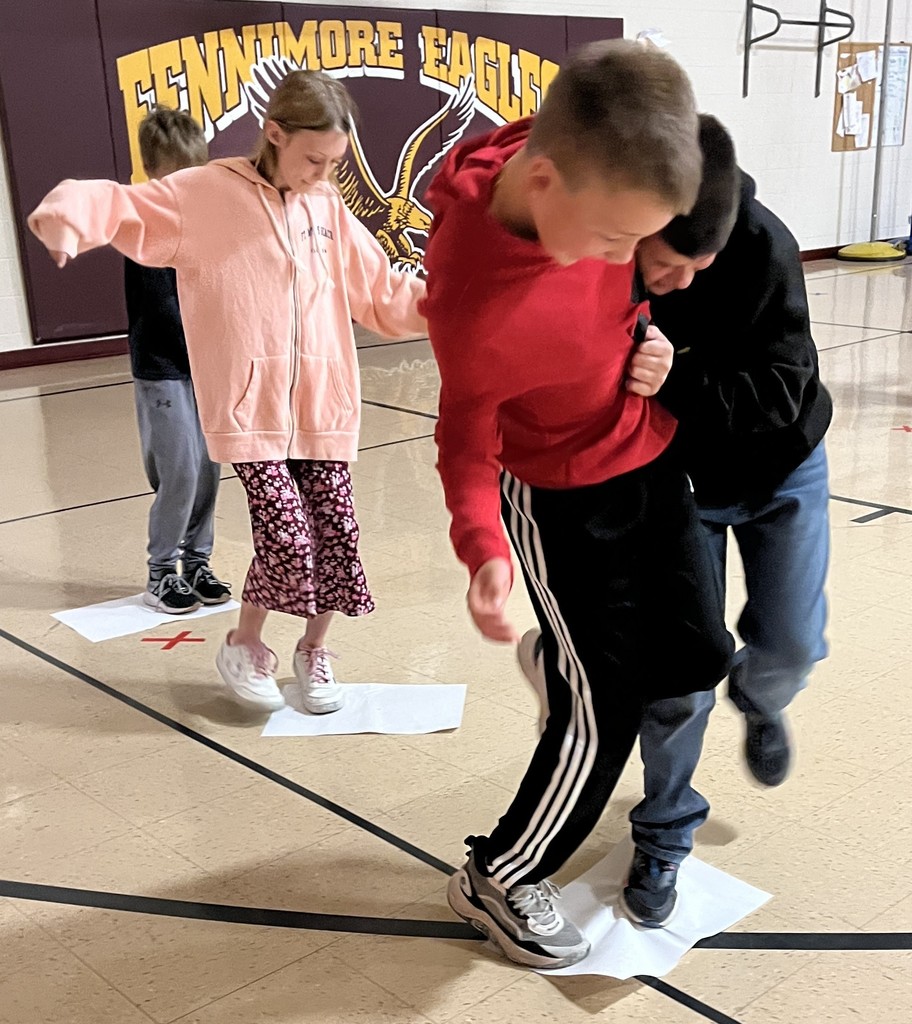 5th grade students stand on paper in gym for the floor is lava game
