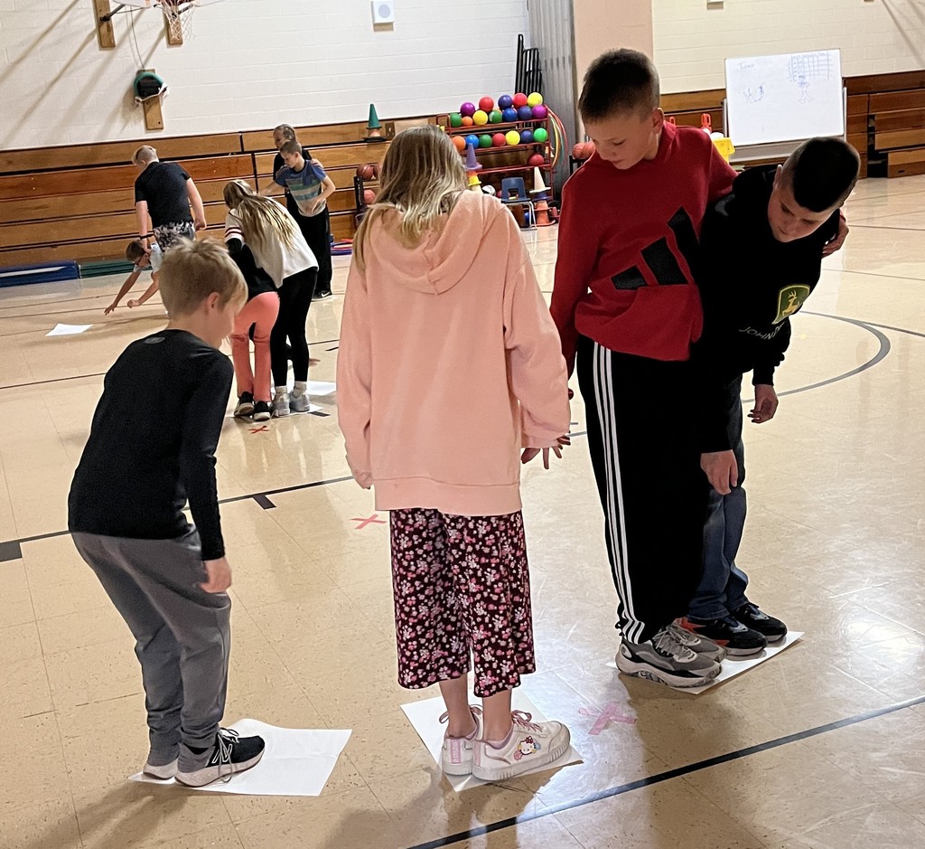 5th grade students stand on paper in gym for the floor is lava game