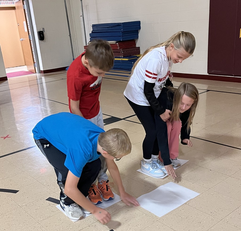 5th grade students stand on paper in gym for the floor is lava game
