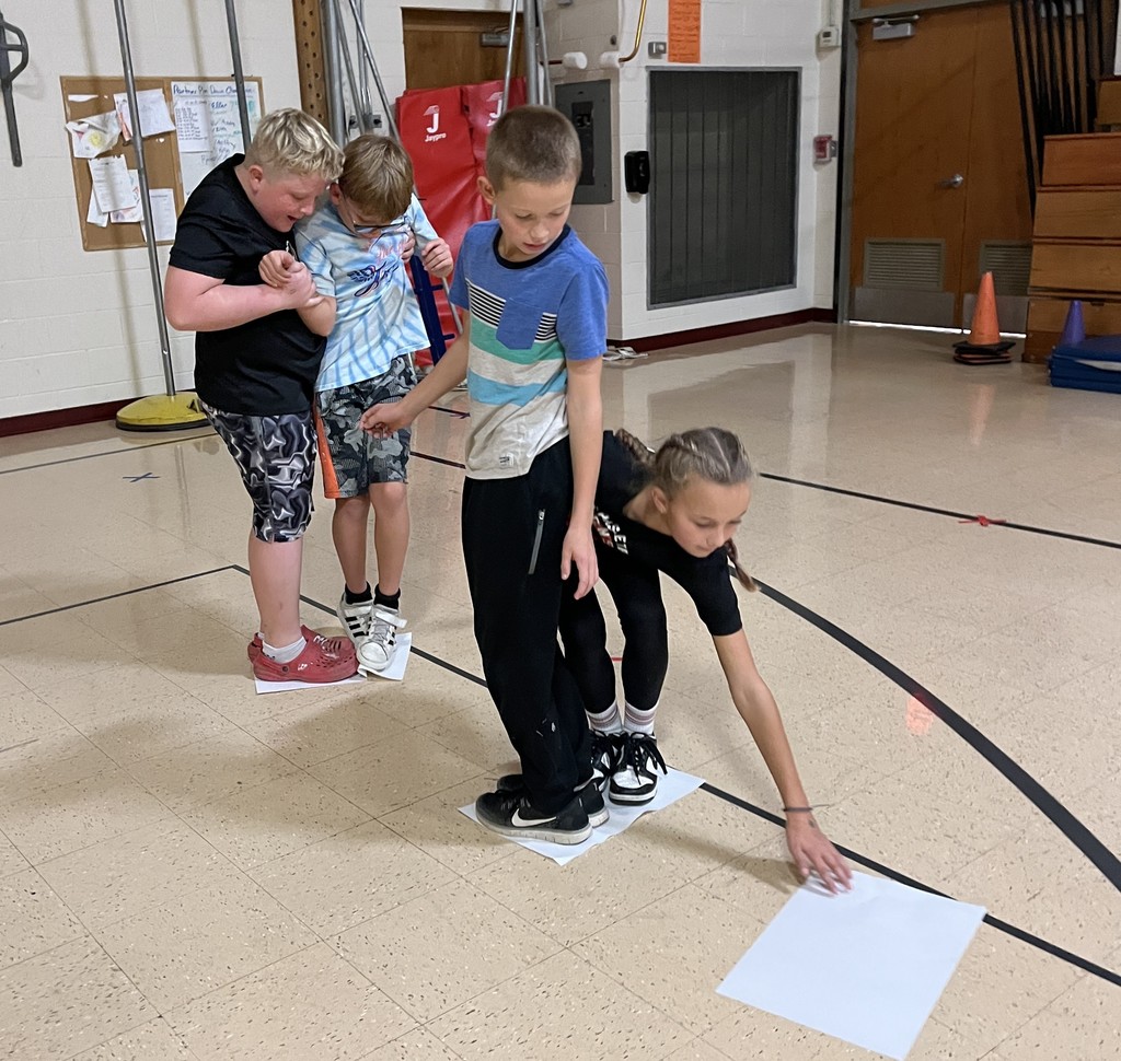 5th grade students stand on paper in gym for the floor is lava game