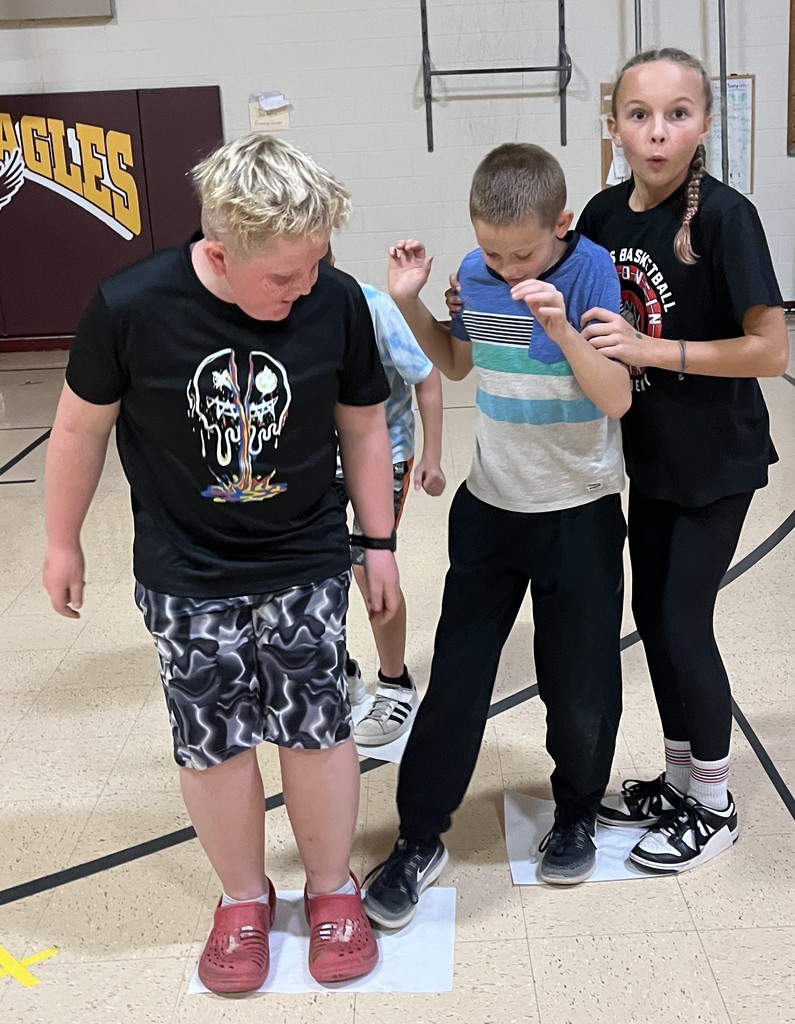 5th grade students stand on paper in gym for the floor is lava game