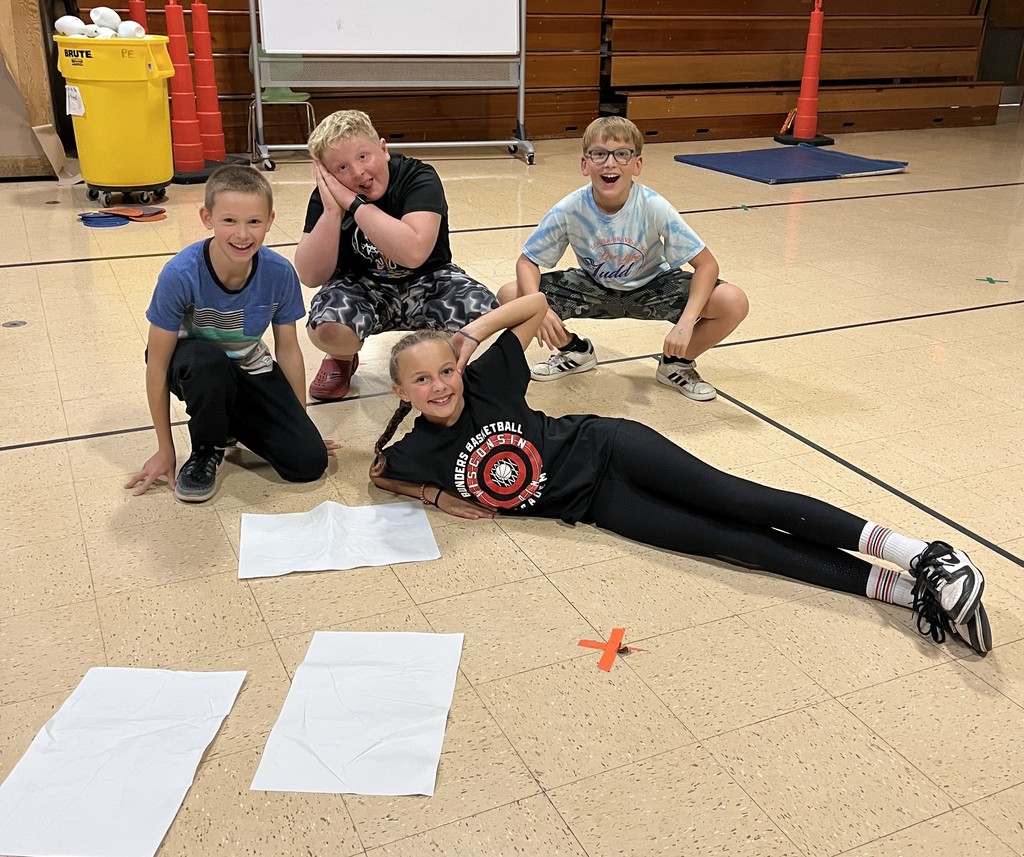 5th grade students stand on paper in gym for the floor is lava game