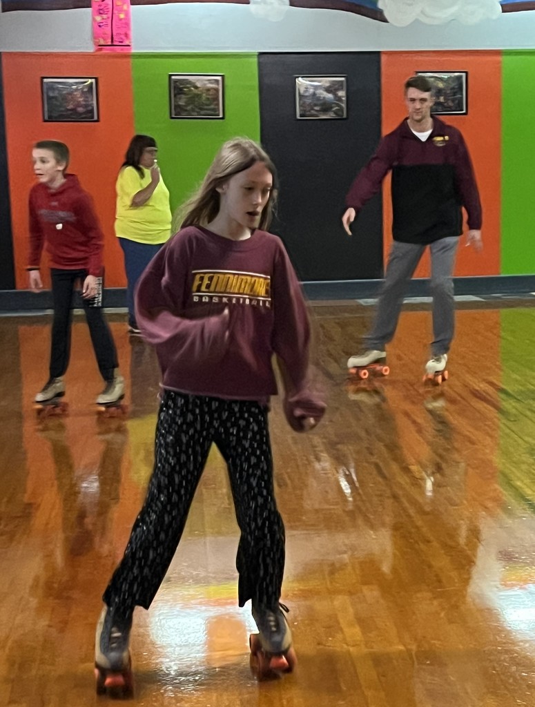students and a teacher skate at the roller rink