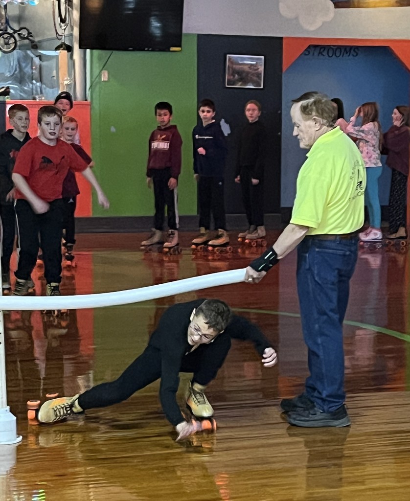 students do the limbo on skates at the roller rink