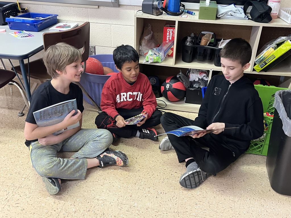 students sit on the floor and read a book together