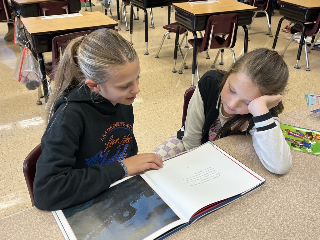 students sit on the floor and read a book together