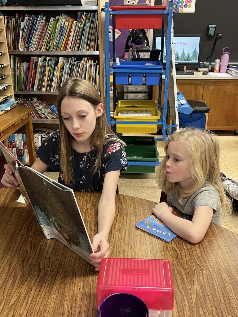 students sit on the floor and read a book together