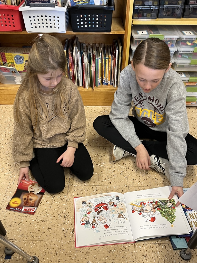 students sit on the floor and read a book together