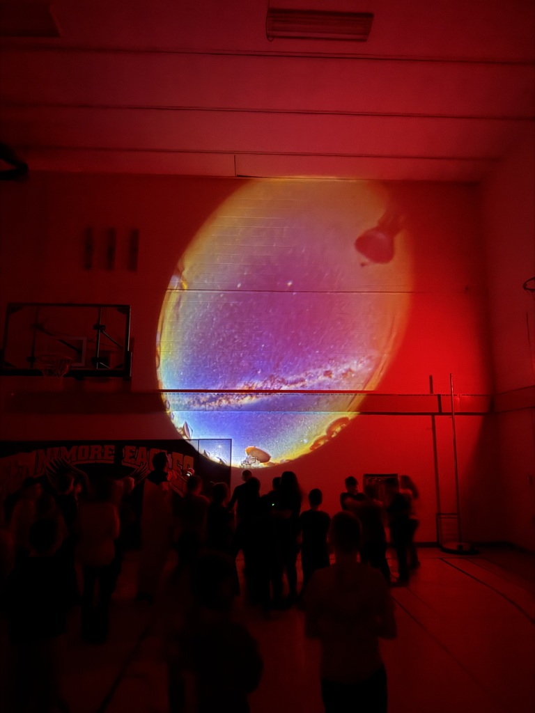 students in gym with lights off and colors on walls