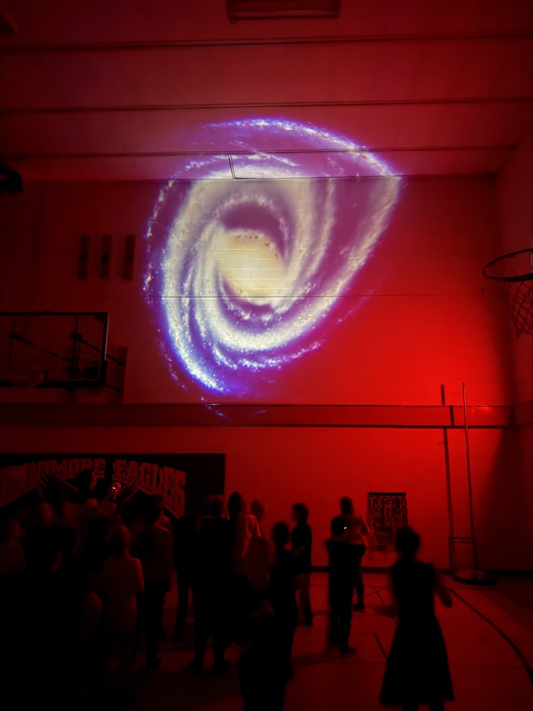 students in gym with lights off and colors on walls