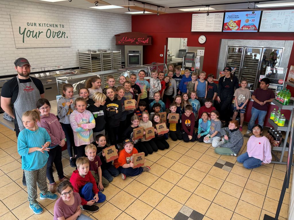 3rd grade students pose for a picture with owner and worker at Papa Murphys