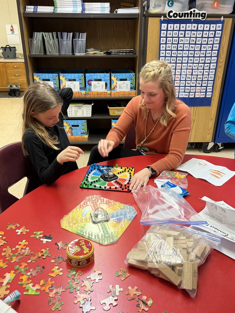 student and a teacher play a game at a desk on family night