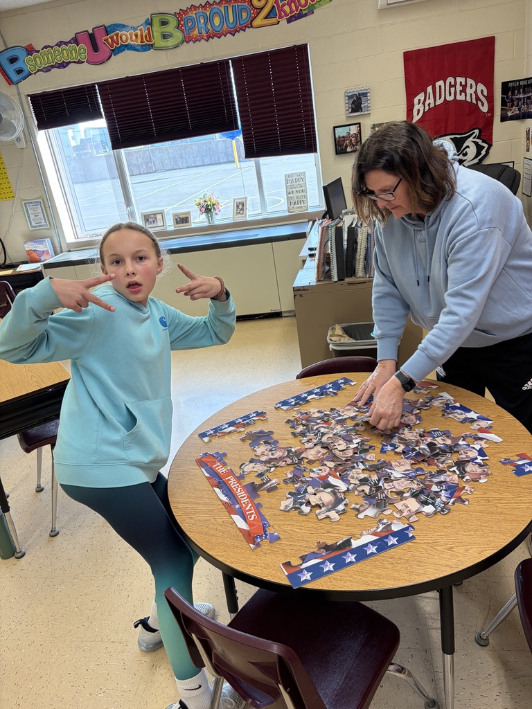 student and a teacher do a puzzle at a desk on family night