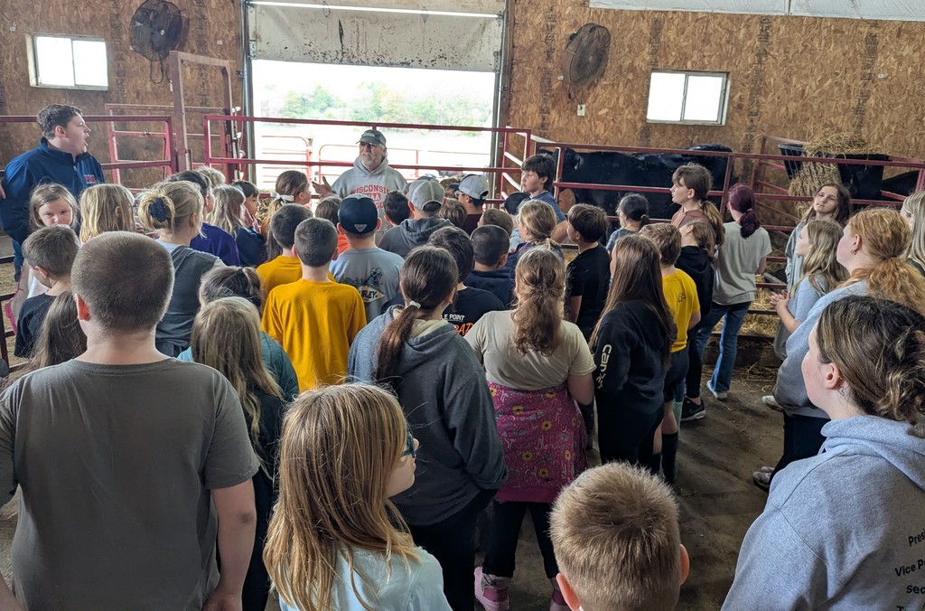 students listen to a farmer talk on their field trip