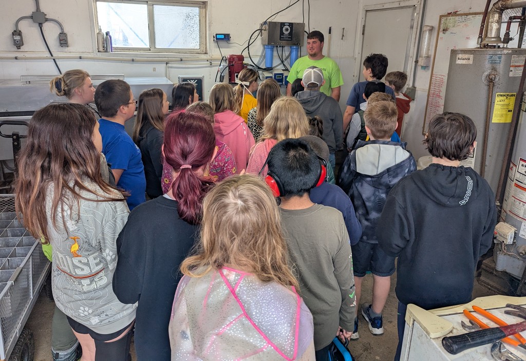 students listen to a worker at a local farm