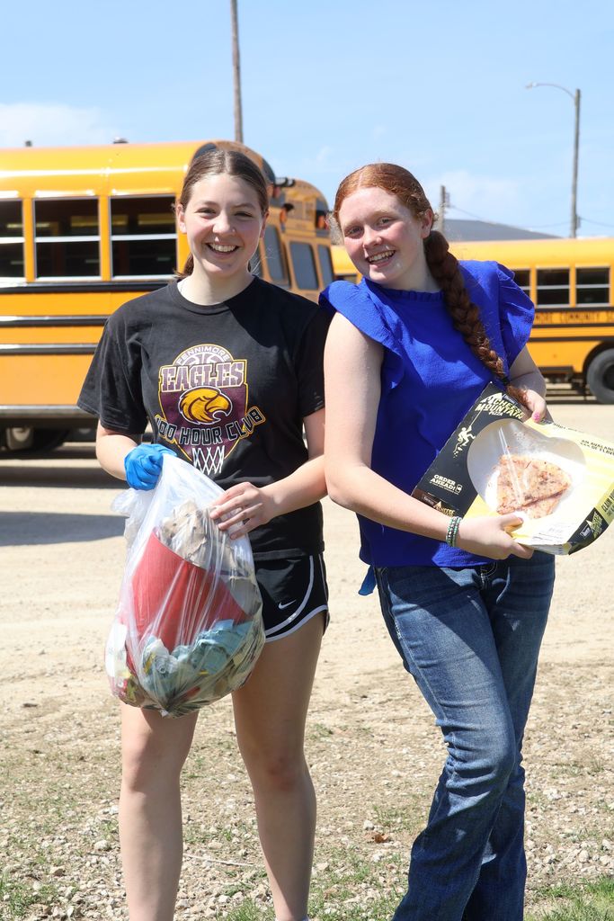 students hold their trash bags from earth day and a pizza box they found