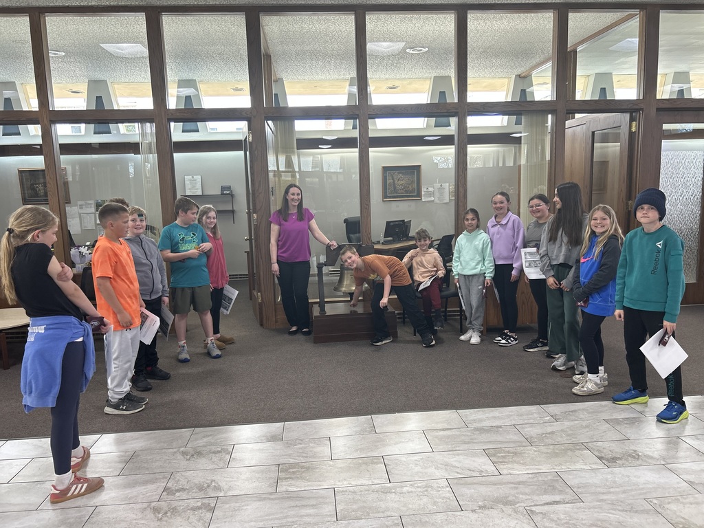 students listen to the bank worker on the tour one student rings the bell