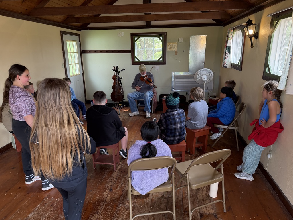 students listen to someone play music at folklore