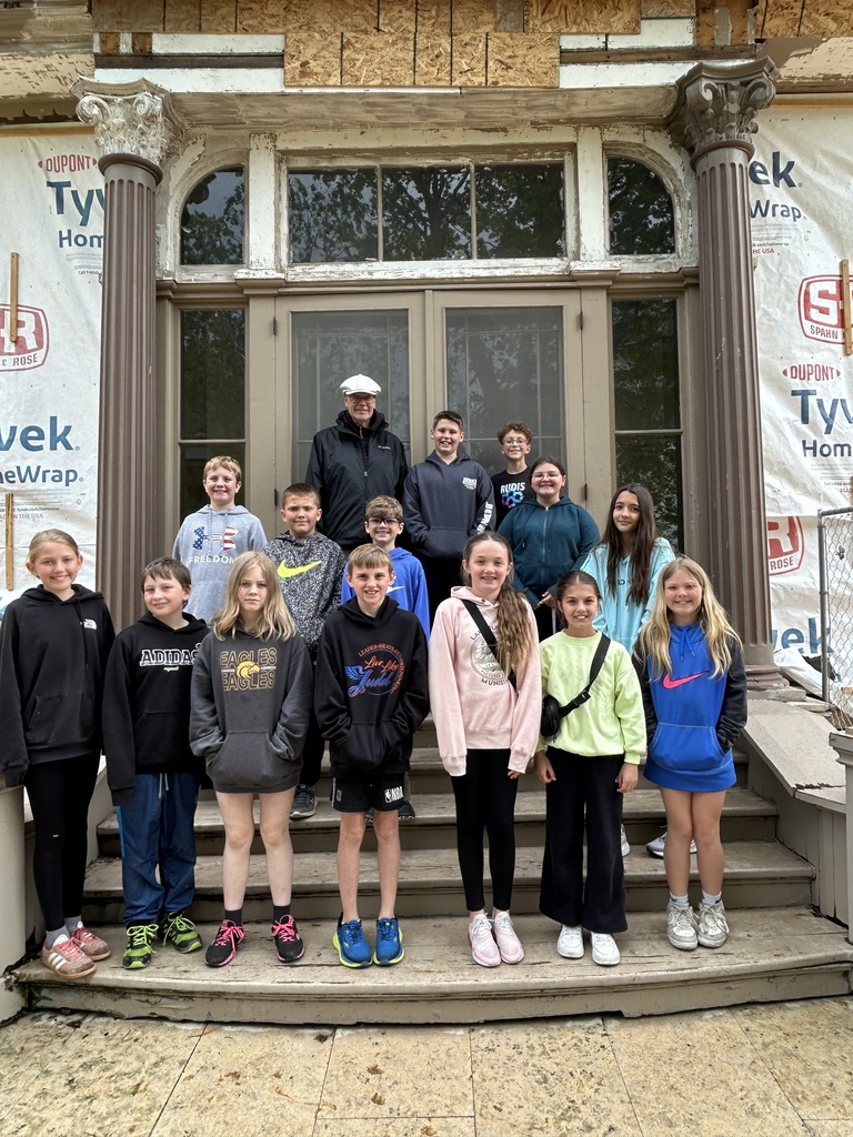students stand outside a building and pose for a picture on their field trip