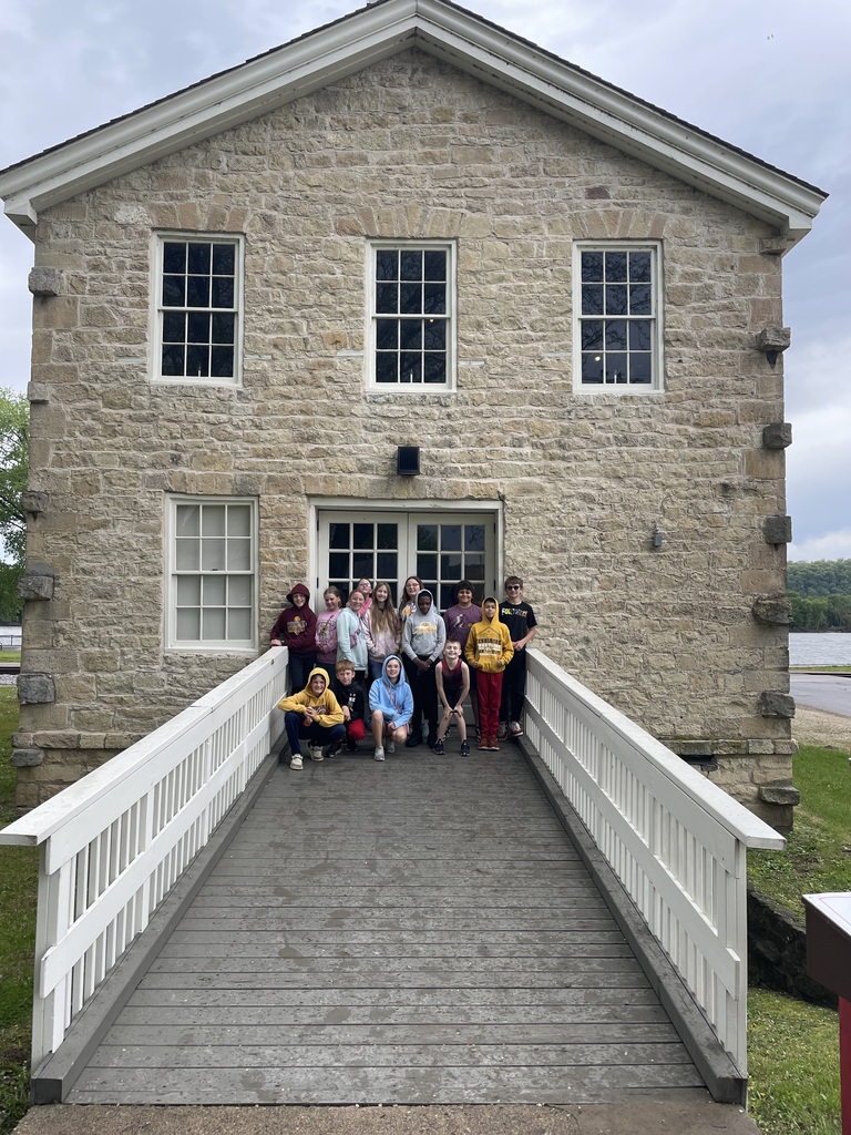 students stand outside a building and pose for a picture on their field trip