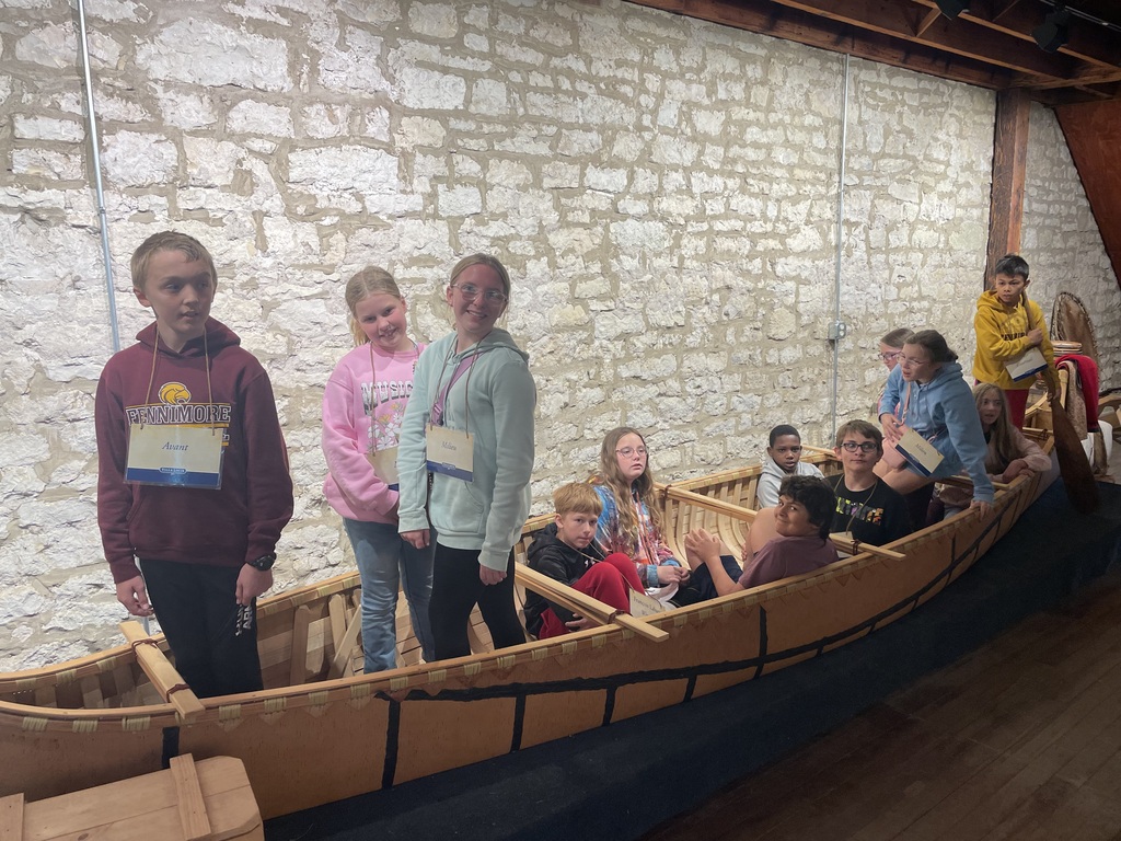 students sit inside a canoe on their field trip