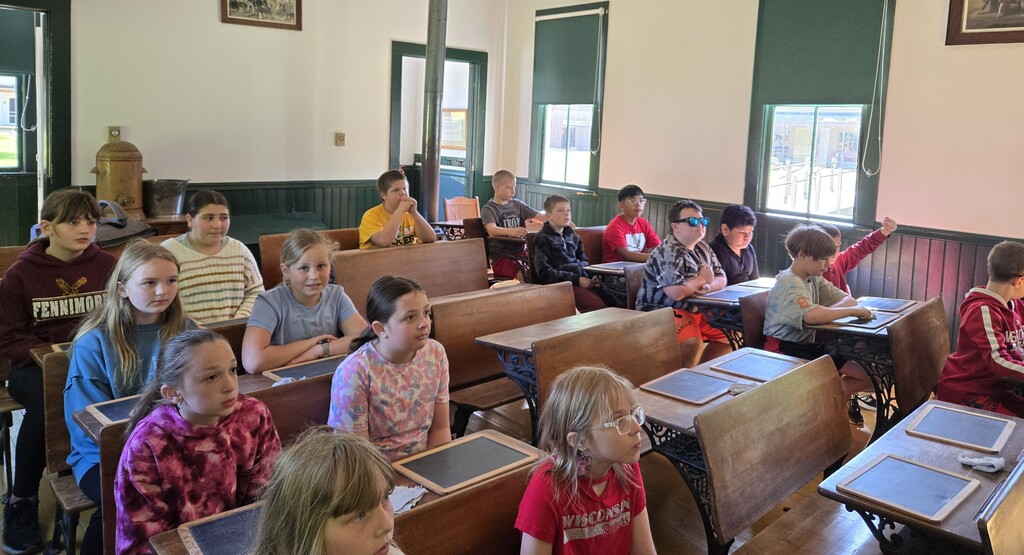 students listen to a teacher in the one room schoolhouse at Stonefield