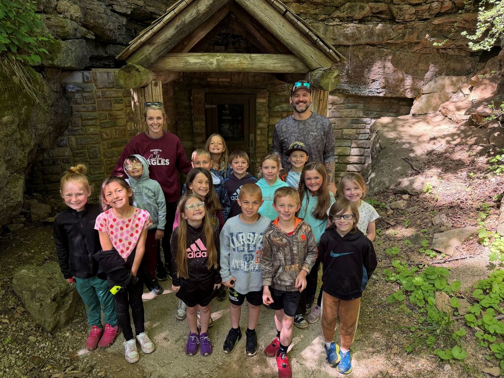 students and teacher and chaperone pose for a picture outside the cave