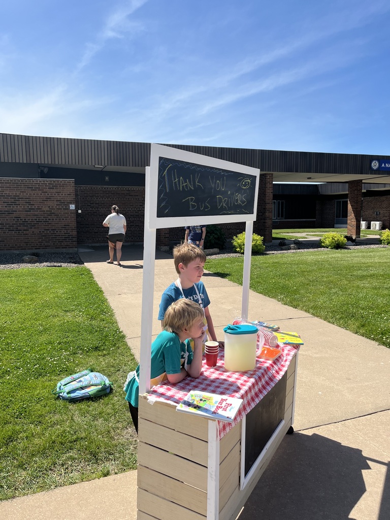 students wait at the stand for the bus drivers so they can deliver their glass of lemonade