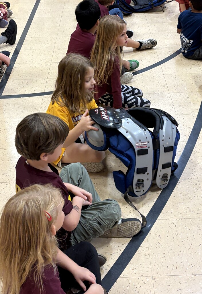 students check out shoulder pads of a player