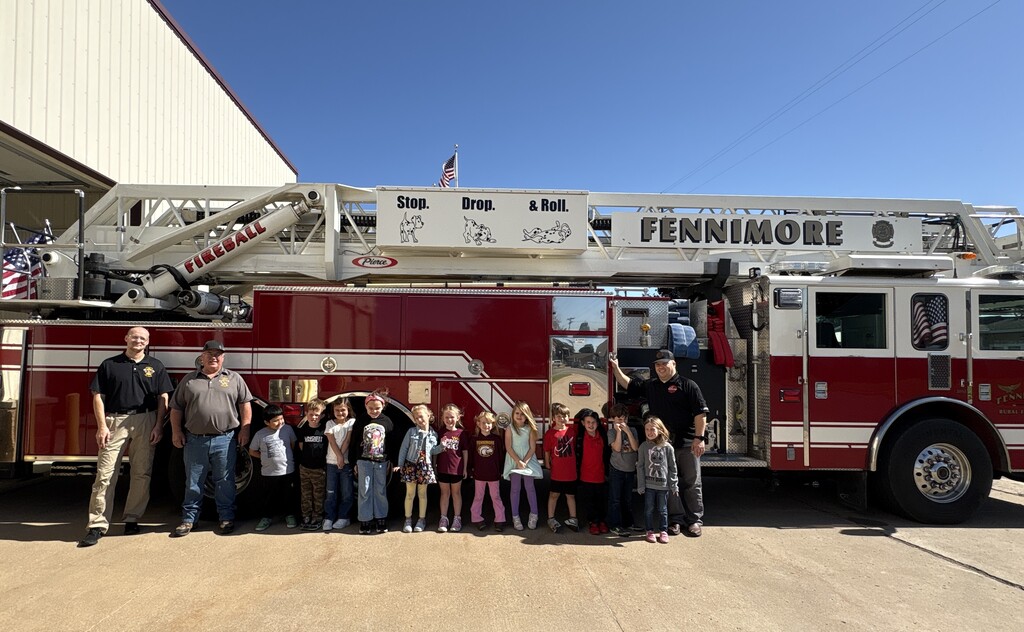 Kindergarten students pose for a picture with firefighters in front of fire engine
