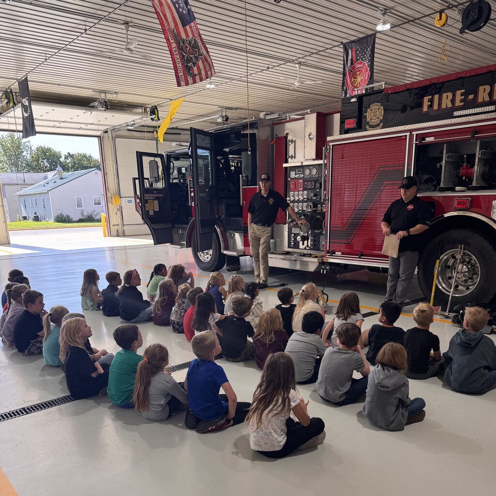 students listen to firefighters at the fire station