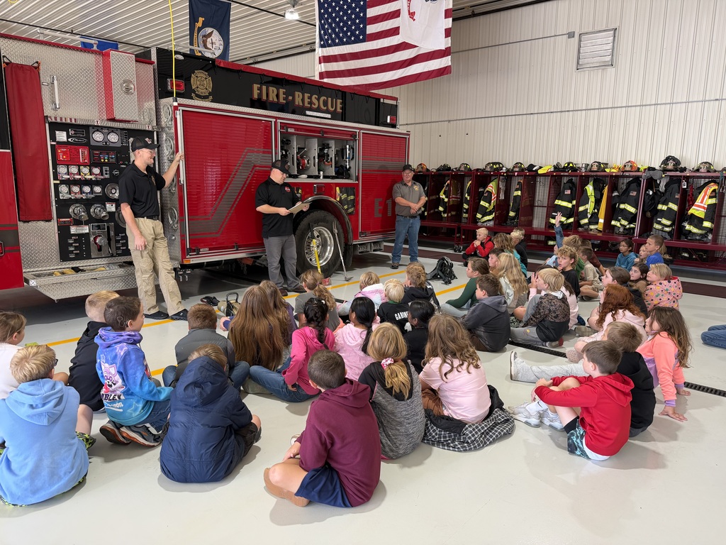 students listen to firefighters at the fire station
