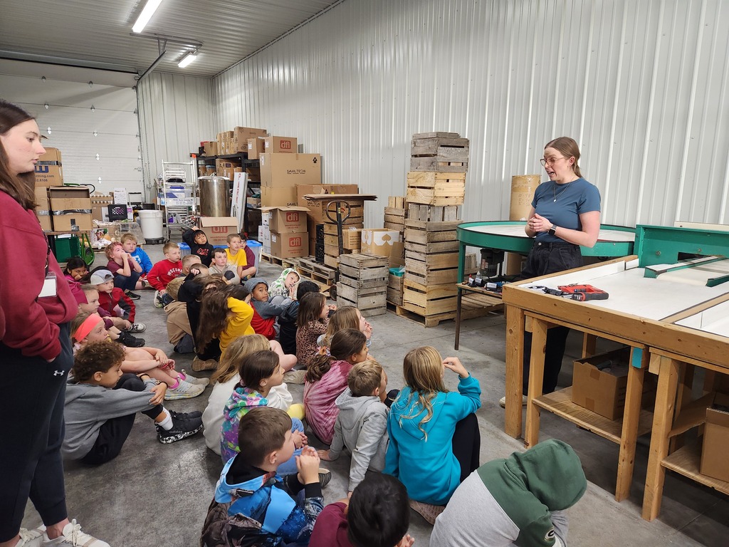 students listen to a worker at the apple orchard