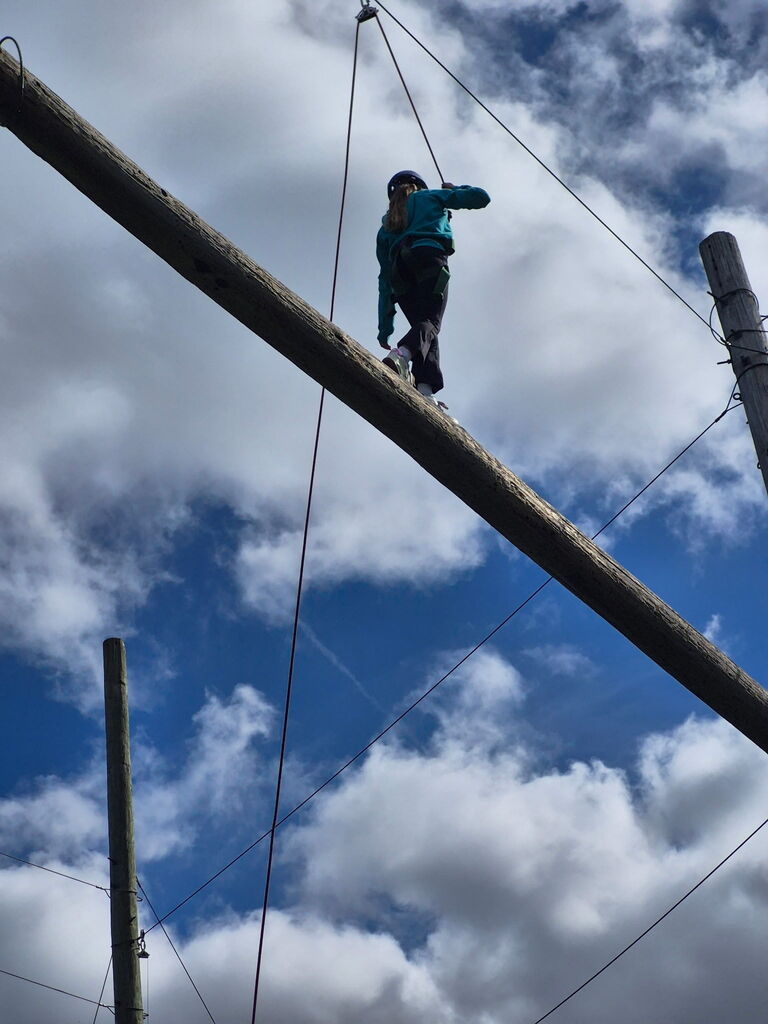 a student is in the harness at bethel horizons field trip and walking up on log