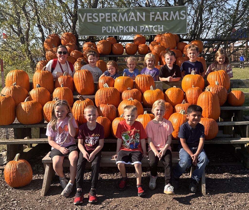 class of students pose for a picture with the pumpkins