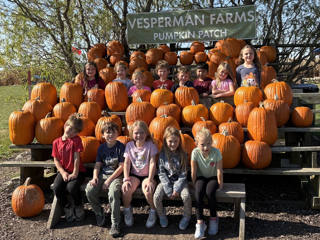 class of students pose for a picture with the pumpkins
