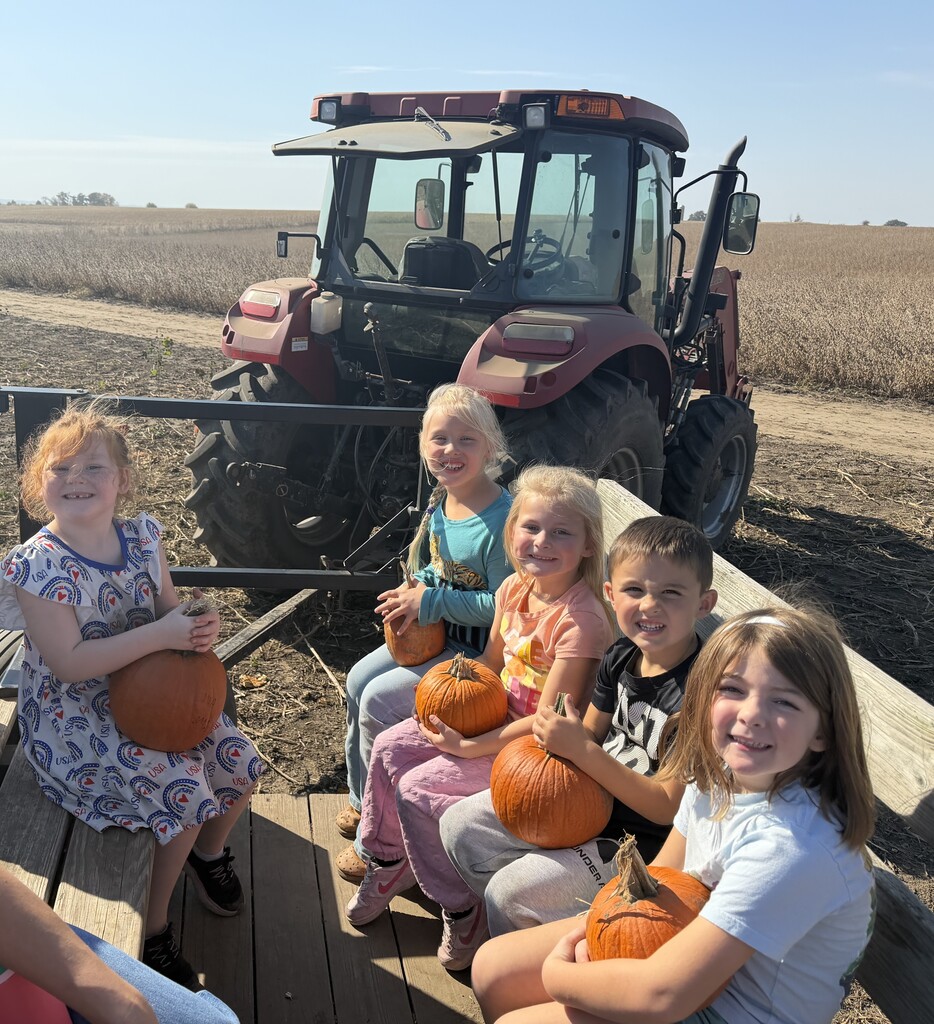 students ride in wagon holding the pumpkin they picked from the patch