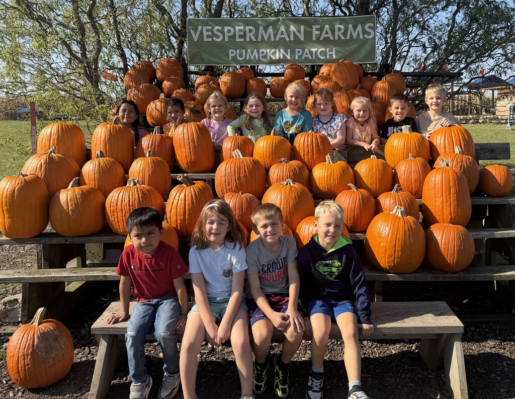 class of students pose for a picture with the pumpkins