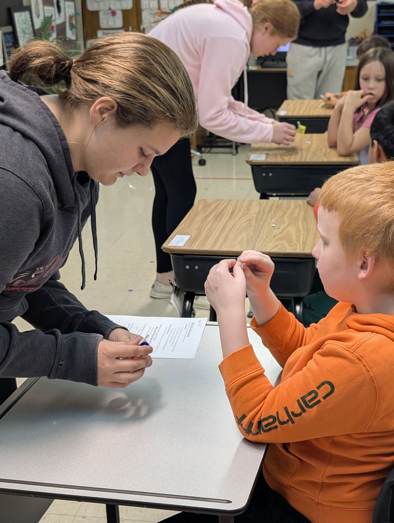 A ffa student helps a younger student make their spider sucker