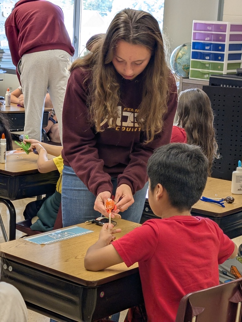 A ffa student helps a younger student make their spider sucker