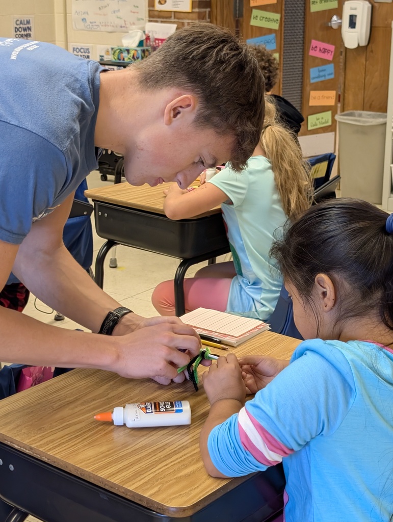 A ffa student helps a younger student make their spider sucker