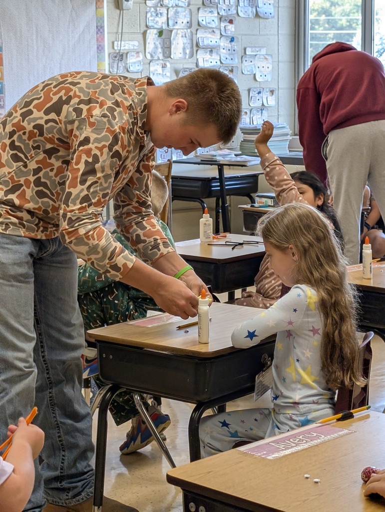 A ffa student helps a younger student make their spider sucker