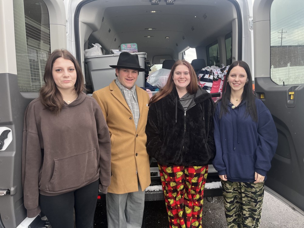Four FHS students standing in front of a van full of donations they are taking to Carriage Town Ministries.