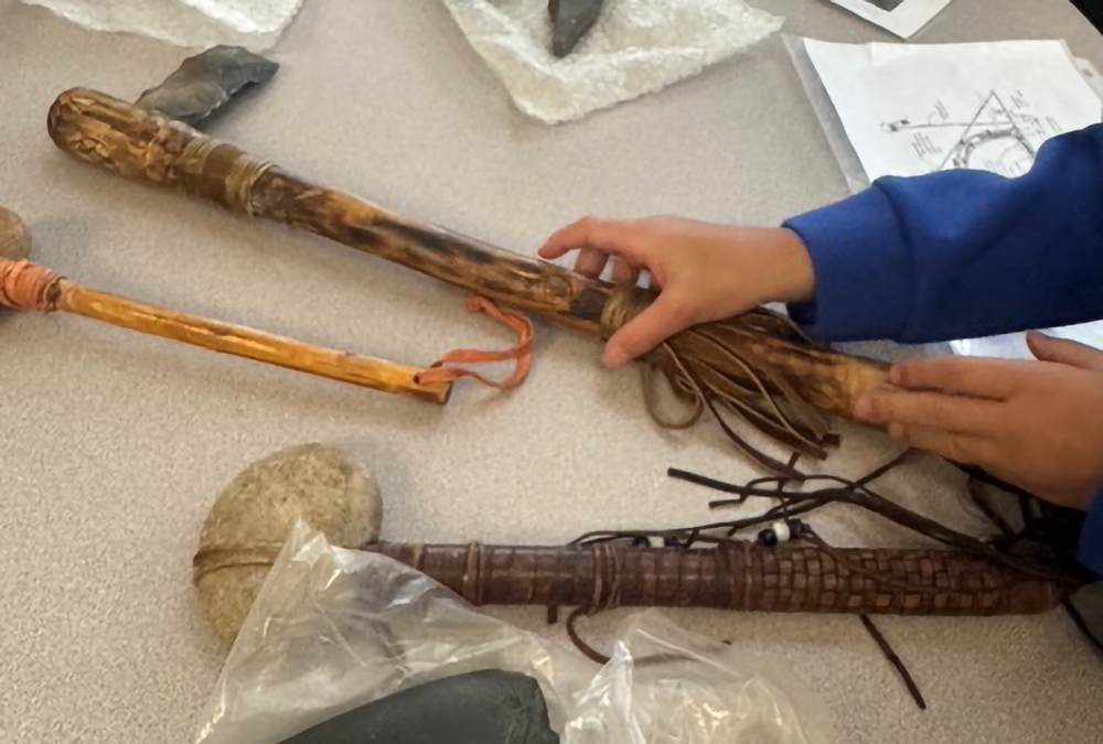students grasps a replica of traditional hunting tools