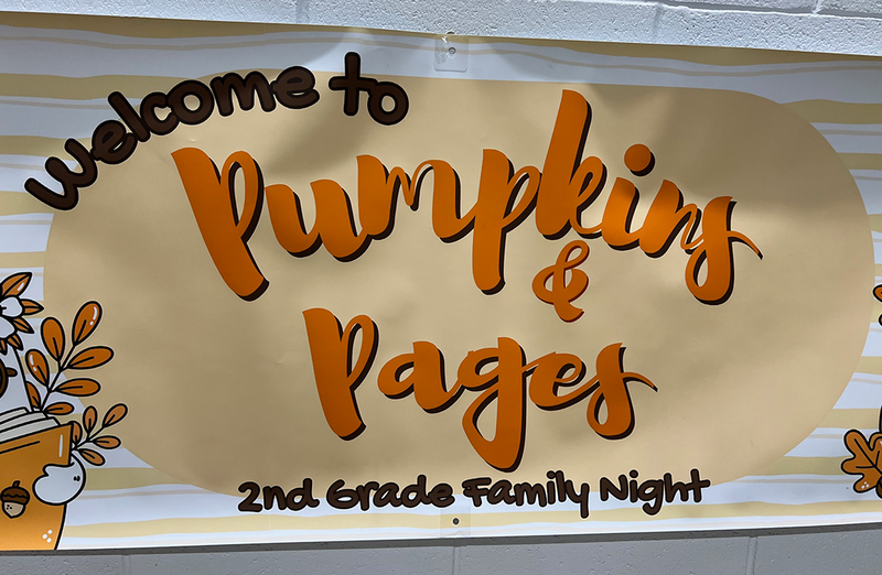 Sign reads "welcome to pumpkins and pages" 2nd grade family night