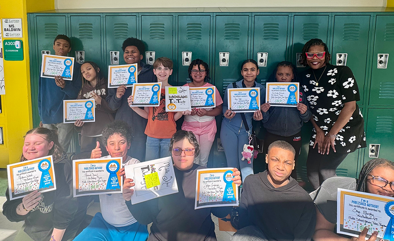 Students sign copies of the books they wrote and published.