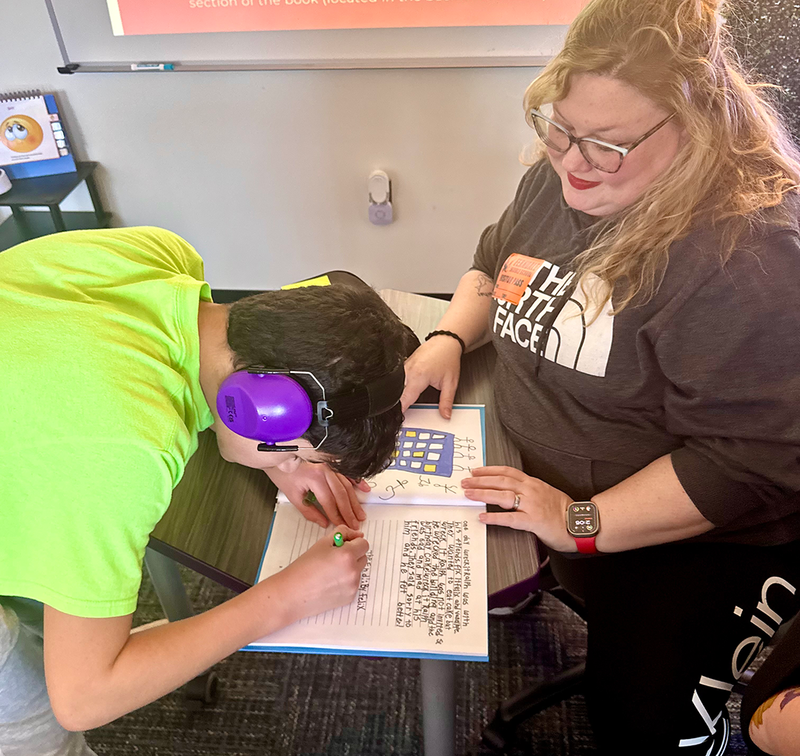Students sign copies of the books they wrote and published.